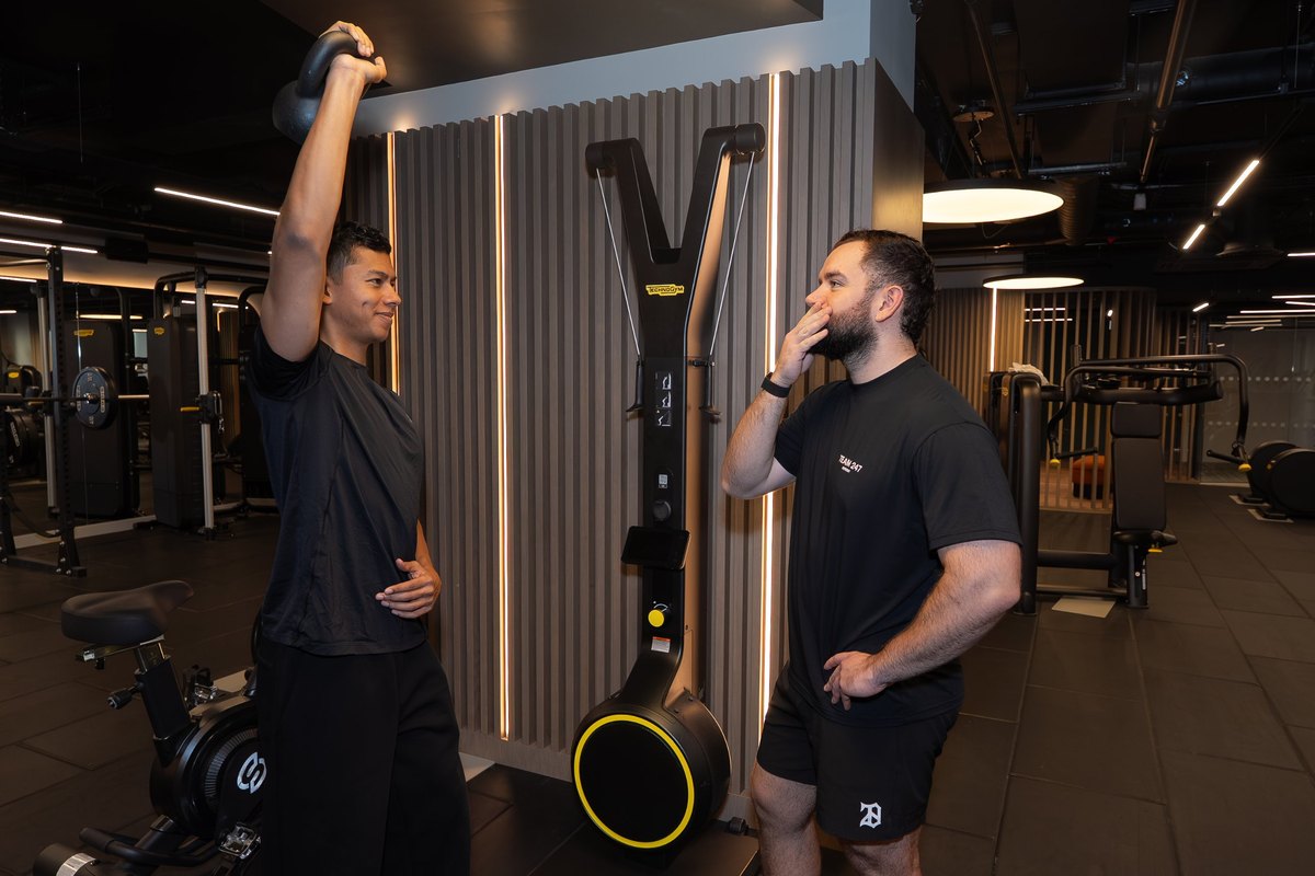 Joel Nathan coaching a patient through a barbell squat in the gym