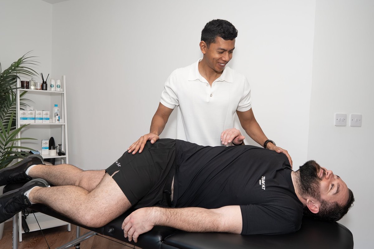 Joel Nathan carrying out a physiotherapy assessment with a patient lying on the treatment table