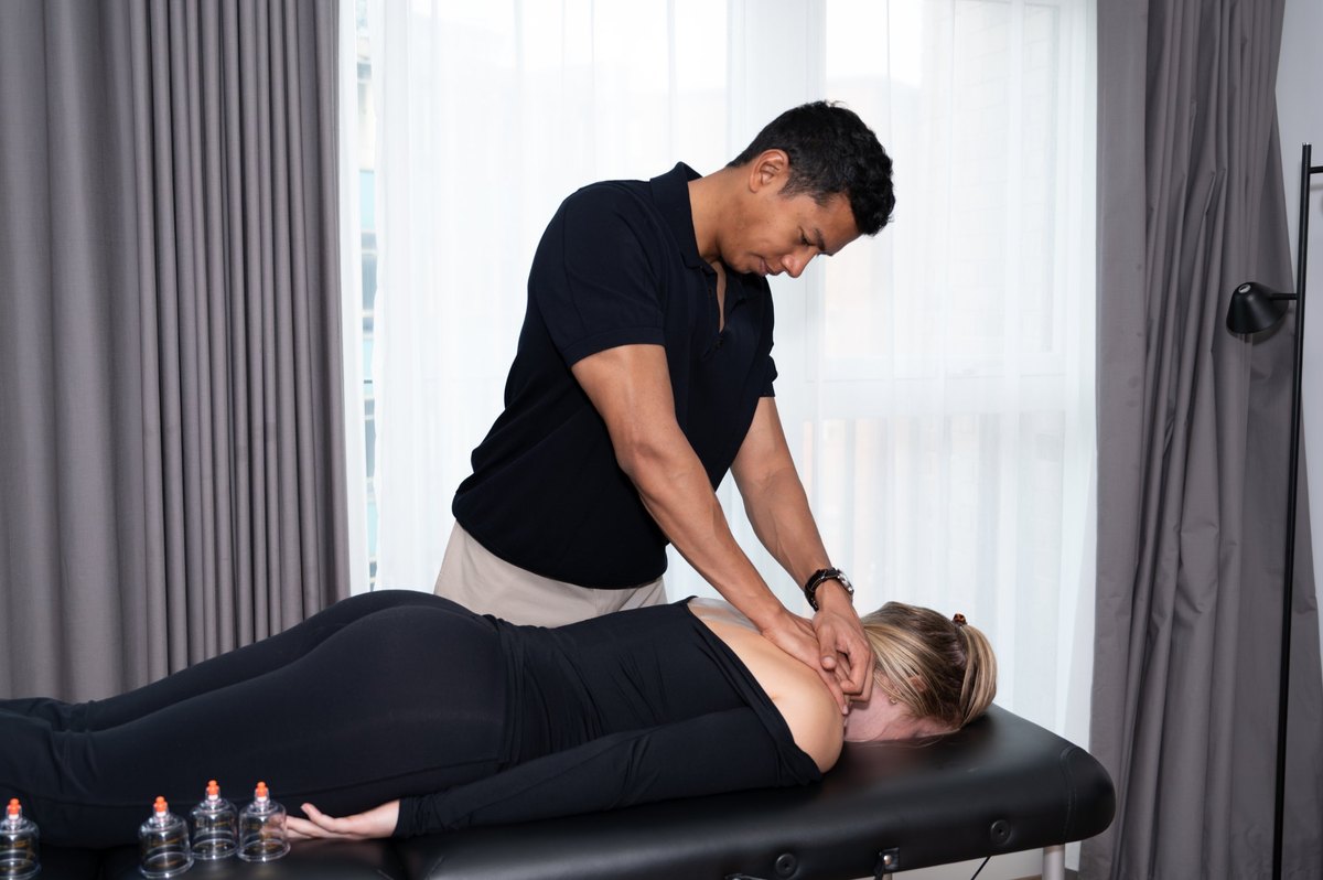 Joel Nathan delivering hands-on massage treatment to a patient's upper back and neck