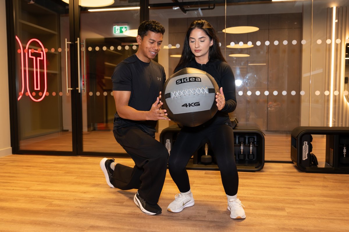 Medicine ball lunge exercise being coached in the gym