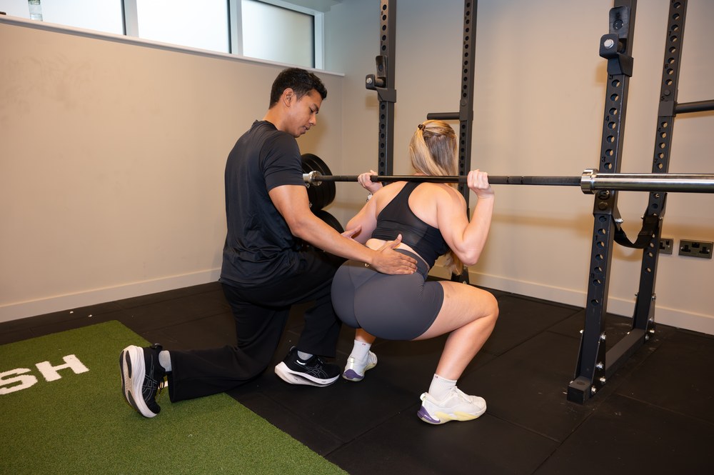 Joel Nathan coaching a controlled squat as part of back pain rehabilitation