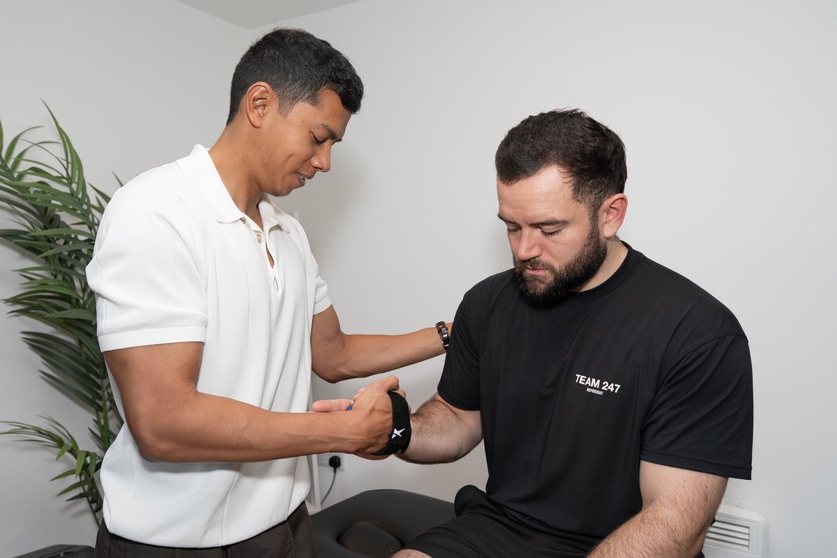 Joel Nathan carrying out a wrist strength assessment on a patient